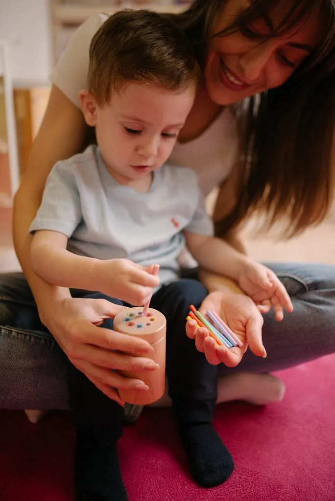 Imagem ilustrativa: adulto e criança brincando com jogo de encaixe no chão de casa